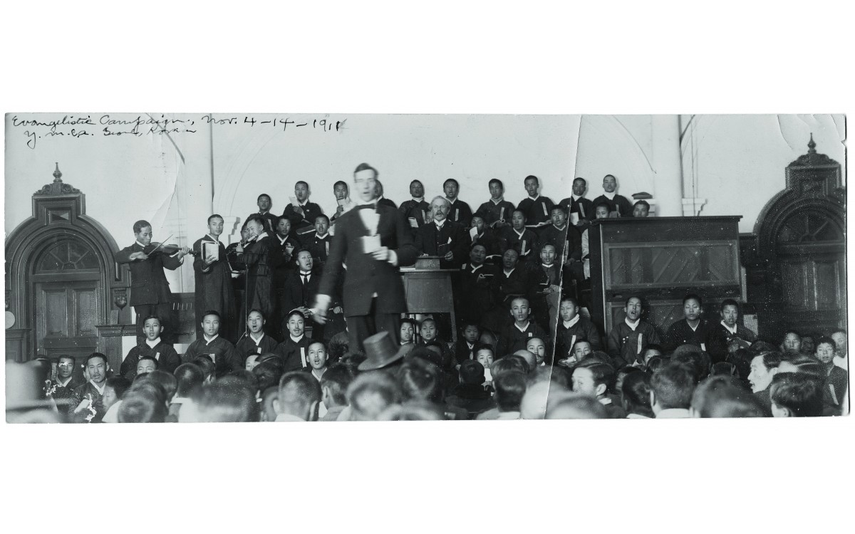 YMCA의 집회 모습(1911). 집회에서 악기 반주에 맞추어 노래를 부르고 있다.<br />단상에 앉은 언더우드 옆으로 이승만의 모습이 보인다.